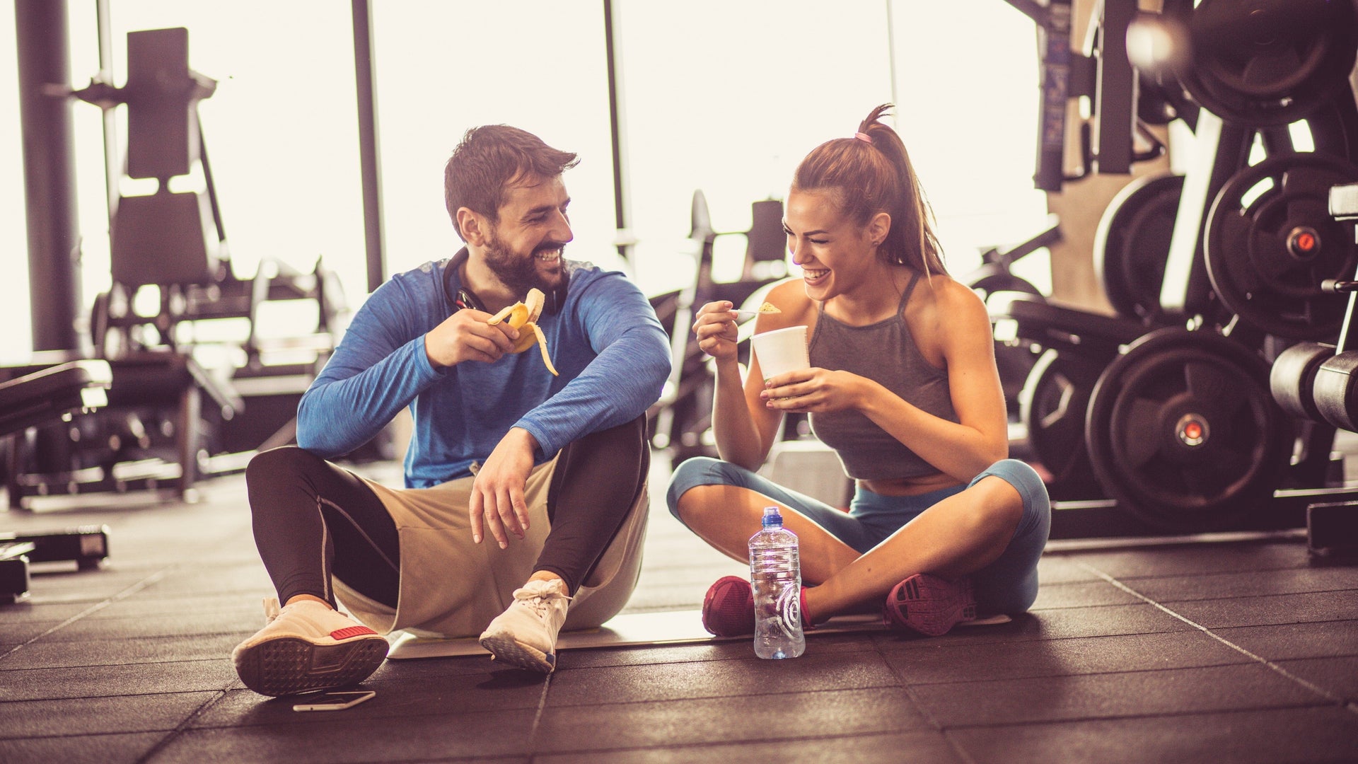 Man and woman enjoying a healthy snack at the gym.