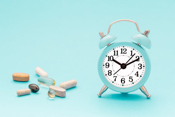Alarm clock and assorted supplements on blue background.