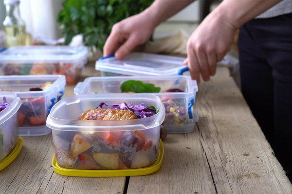 Meal prep with healthy food in plastic containers on a wooden table.