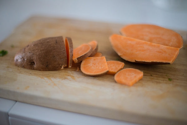 Sliced sweet potato on a wooden cutting board.