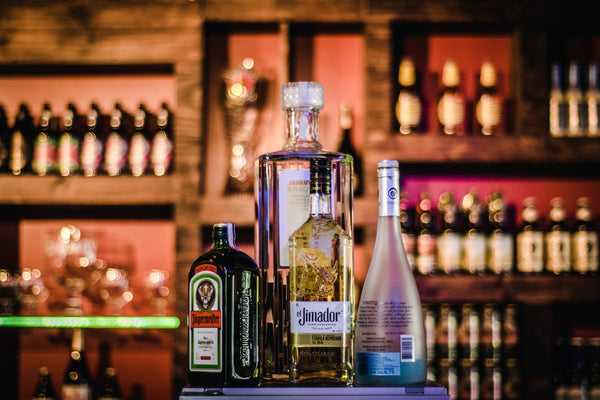 Bottles of various liquor brands displayed on a bar shelf.