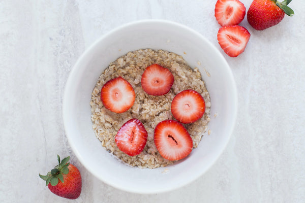 Bowl of oatmeal topped with fresh strawberry slices.