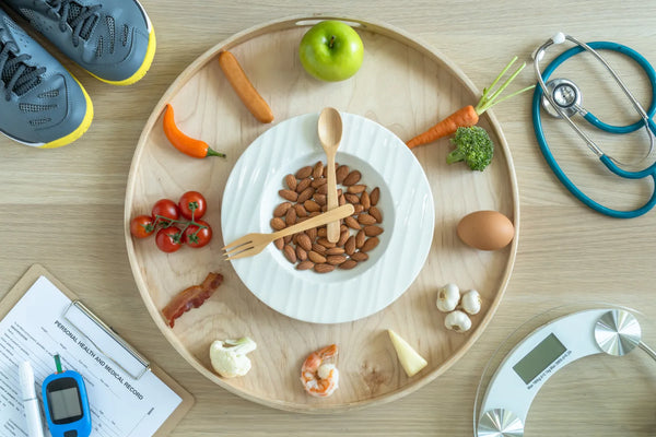 Healthy diet and fitness concept with almonds, vegetables, stethoscope, and running shoes on a tray.