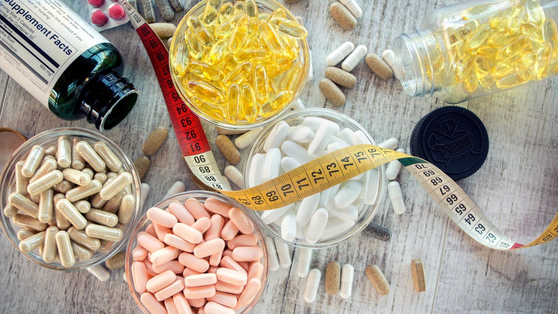 Various dietary supplements and pills with measuring tape.