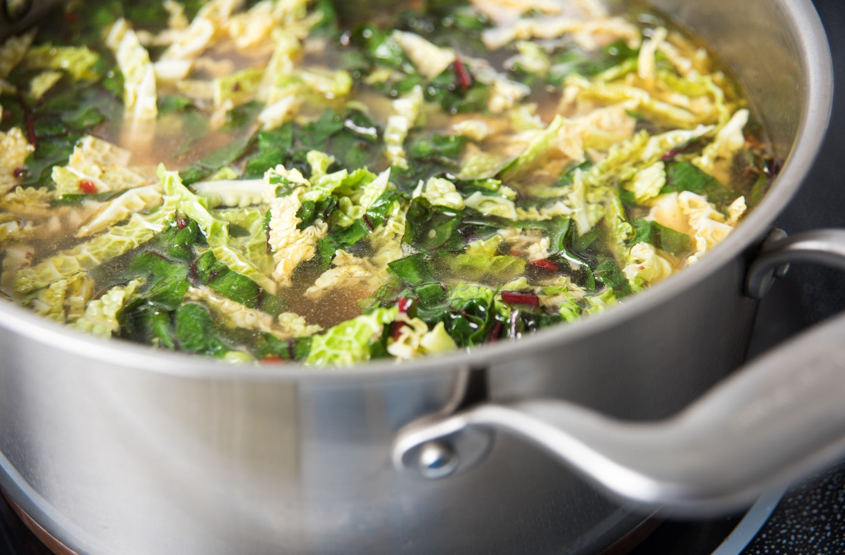 Pot of healthy green vegetable soup cooking on stovetop.